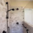 Accessible walk-in shower with a handheld shower head, grab bars, and adjustable slide bar for aging-in-place bathroom design.